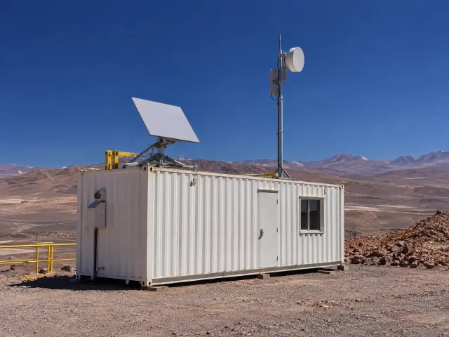 Antena satelital y mástil de radioenlace sobre un contenedor de oficina en una faena remota